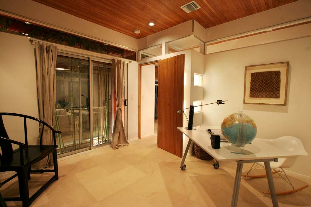 Modern home office with wooden desk, globe, and natural light from sliding doors overlooking trees