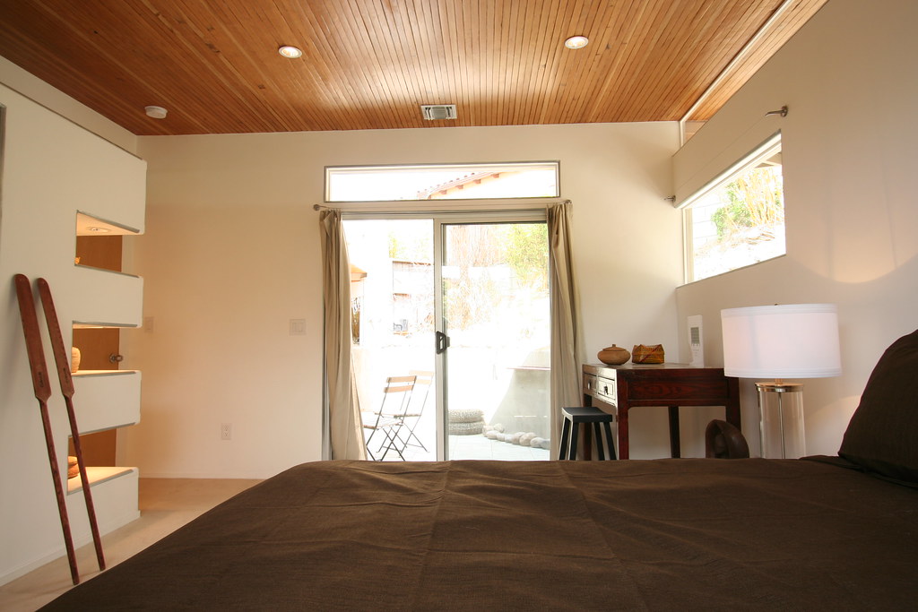 Modern bedroom with wooden ceiling and minimalist furnishings in natural light